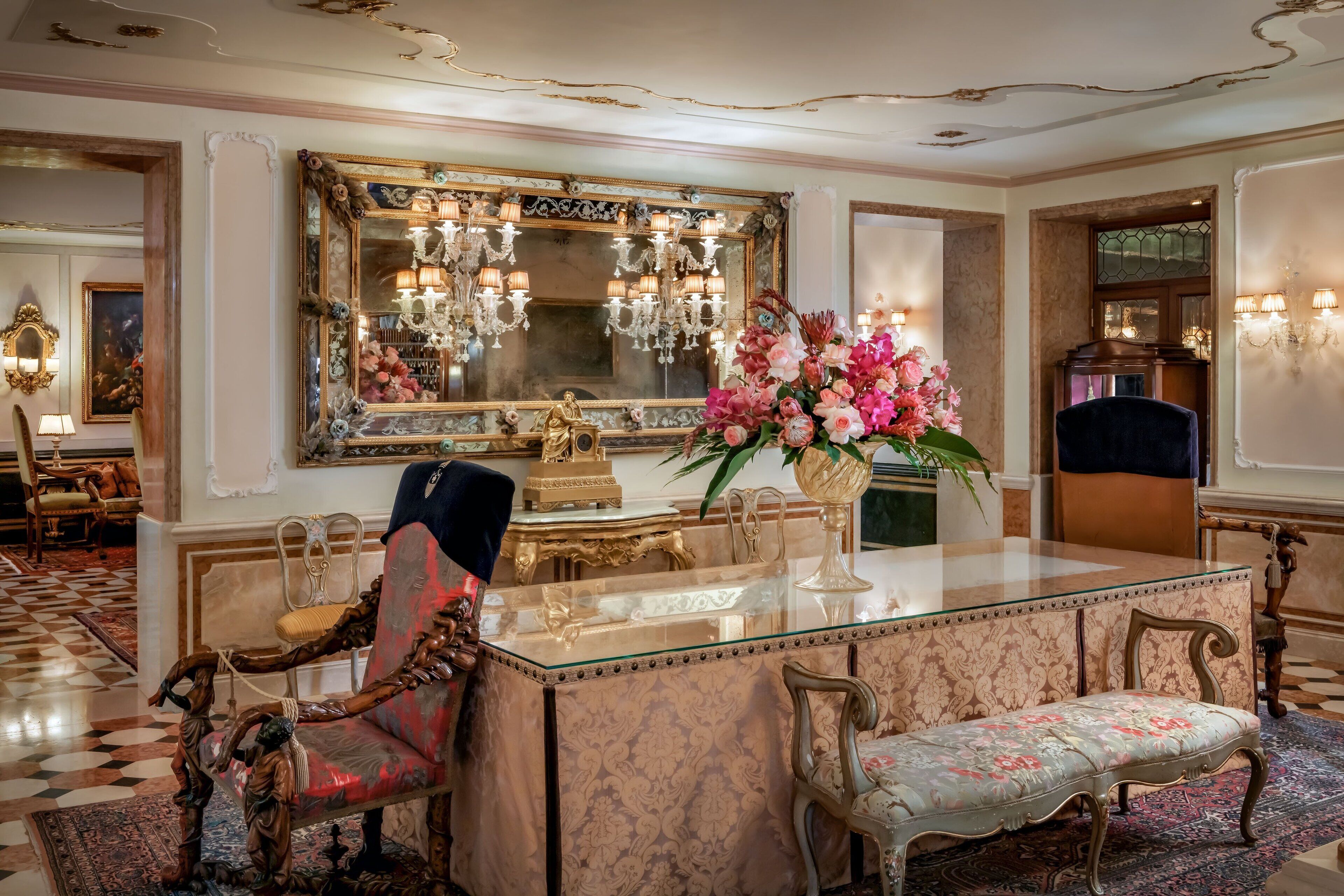 Une chambre luxueuse dotée d’un bar en marbre, de meubles richement décorés et d’un grand miroir orné d’un cadre floral.