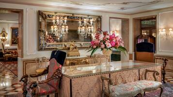 A luxurious room with a marble bar, ornate furniture, and a large mirror with a floral frame.