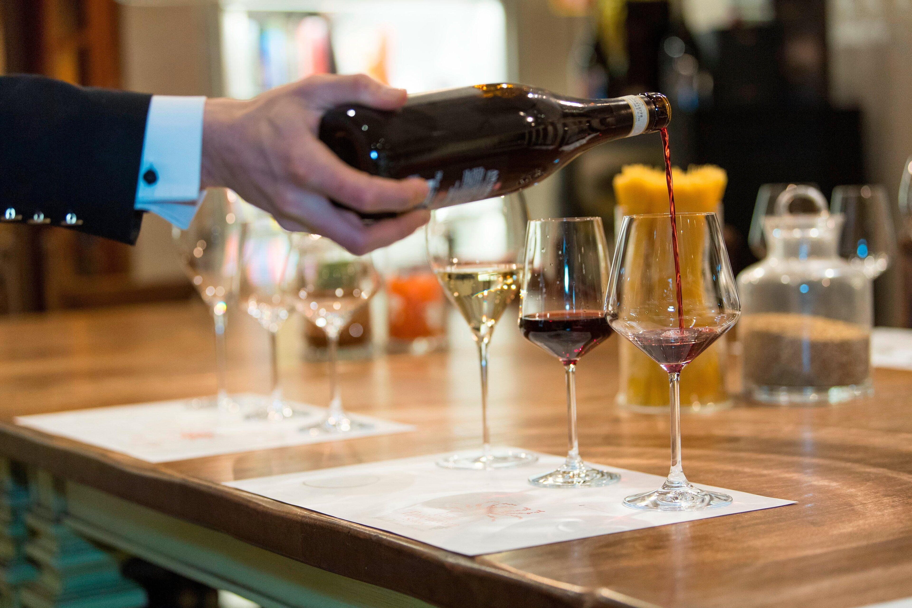 Alguém servindo vinho em um copo em um bar.