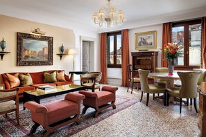 A well-furnished living room with a sofa, armchairs, a coffee table, and a dining area with chairs and a table.