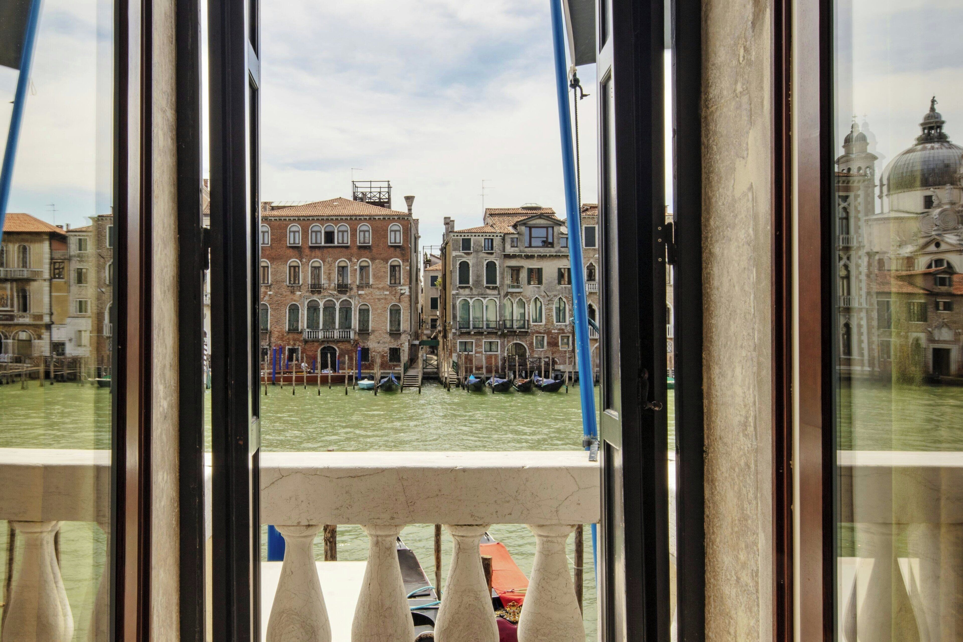 Vista da un balcone su un canale, con edifici storici e gondole.