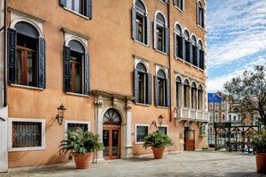 A historic building with a sign reading "GRITTI PALACE HOTEL" and a "GONDOLE" sign indicating a canal-side location.