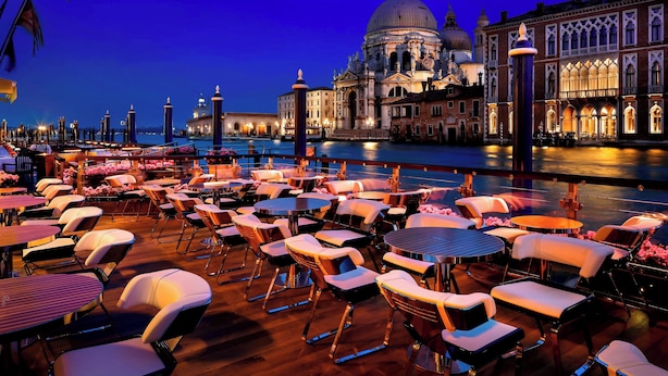 A terrace with tables and chairs, a view of a historic building with a dome, and a body of water in the background. - The Gritti Palace, a Luxury Collection Hotel, Venice (Venice)