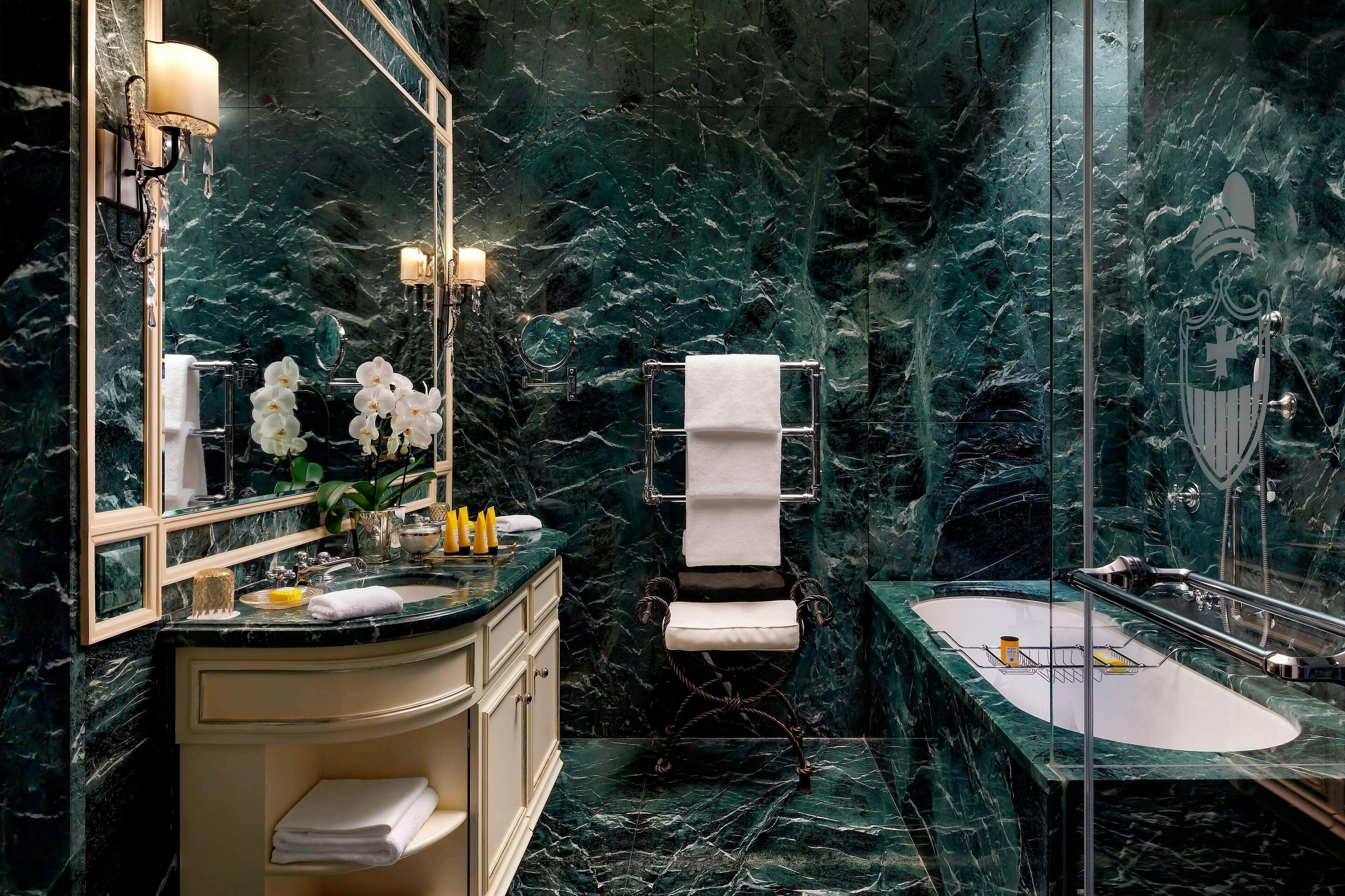 Un baño con lavamanos de mármol, toallero y bañera.