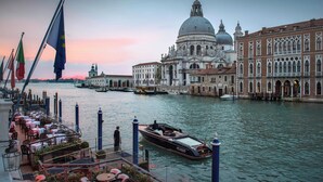 A waterfront restaurant with outdoor seating overlooking a canal, a gondola, and historic buildings in the background. - The Gritti Palace, a Luxury Collection Hotel, Venice (Venice)