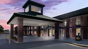 A modern hotel with a covered entrance, brick facade, and large windows.