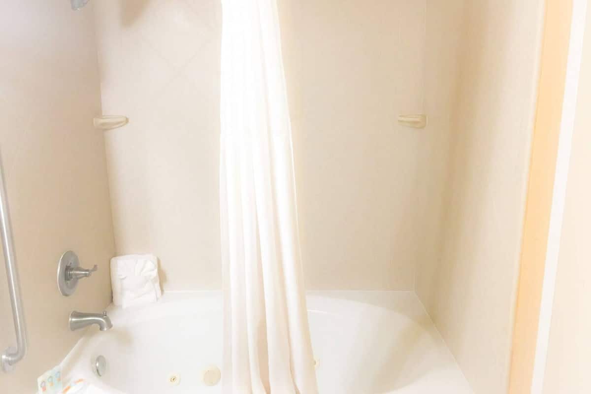 A bathroom with a bathtub, a shower, and a handrail.