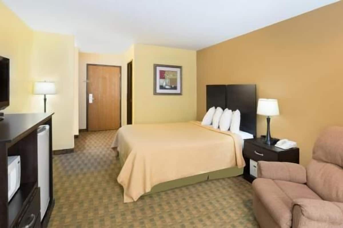 A hotel room with a bed, a desk, a chair, a television, and a framed picture on the wall.