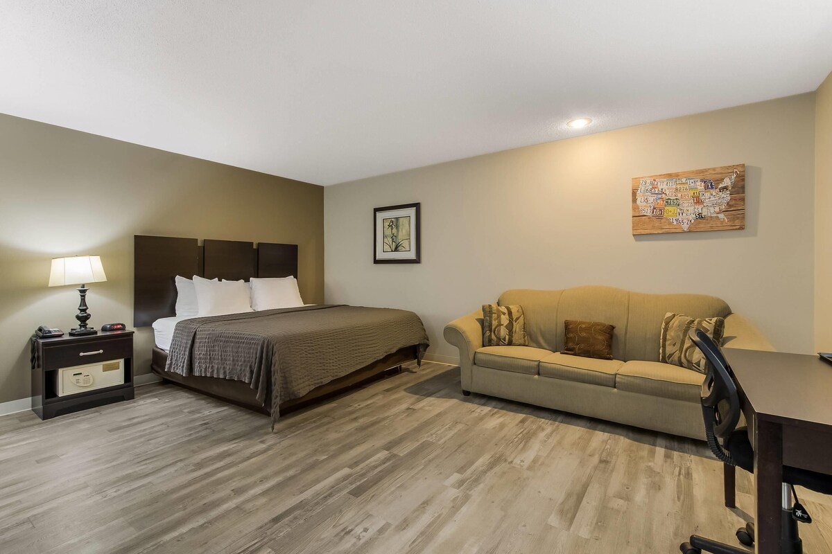 A bedroom with a bed, bedside table, lamp, and a map on the wall.