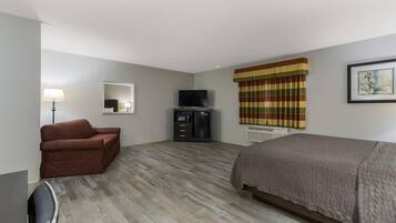 Una habitación de hotel con cama, sofá, televisión, escritorio y espejo.