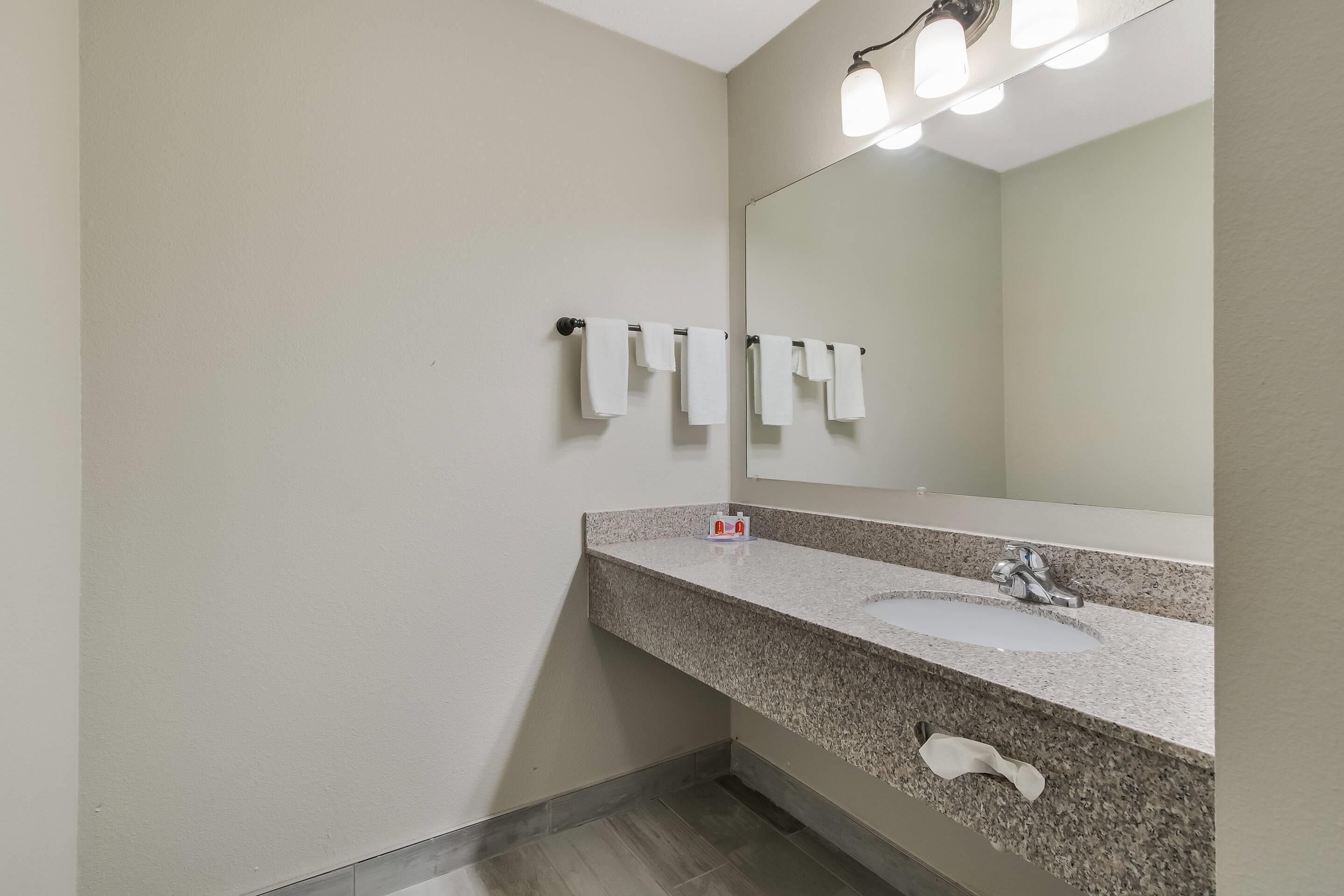 A bathroom with a granite countertop, a sink, a mirror, and a towel rack.