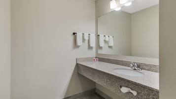 A bathroom with a granite countertop, a sink, a mirror, and a towel rack.