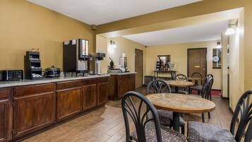 Una cocina con estación de café, armarios de madera y un comedor con sillas y una mesa.
