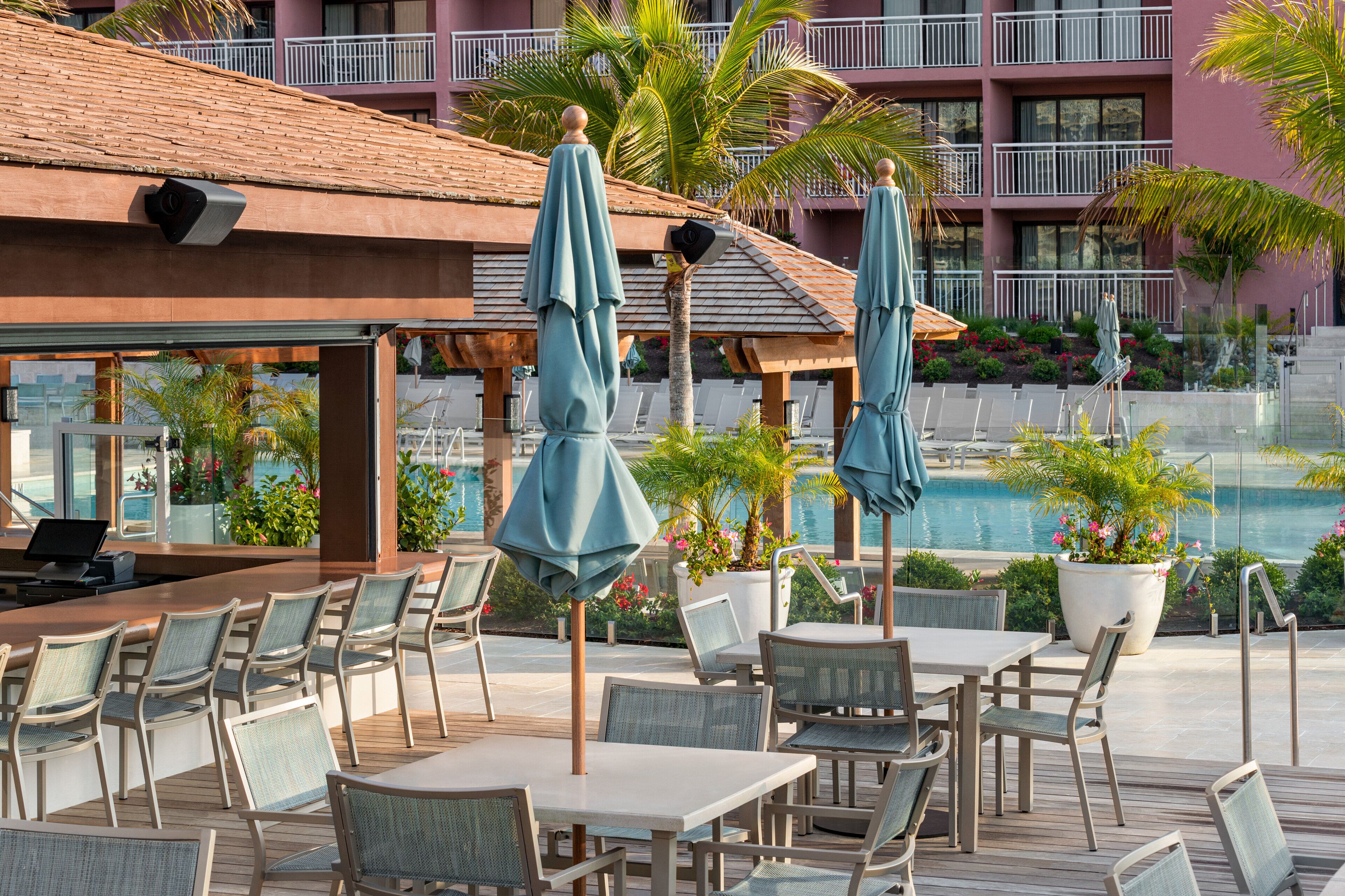 A poolside area with outdoor seating, umbrellas, and a view of the pool and building in the background.