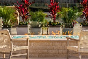 An outdoor seating area with two wicker chairs, a stone table, and a fire feature.