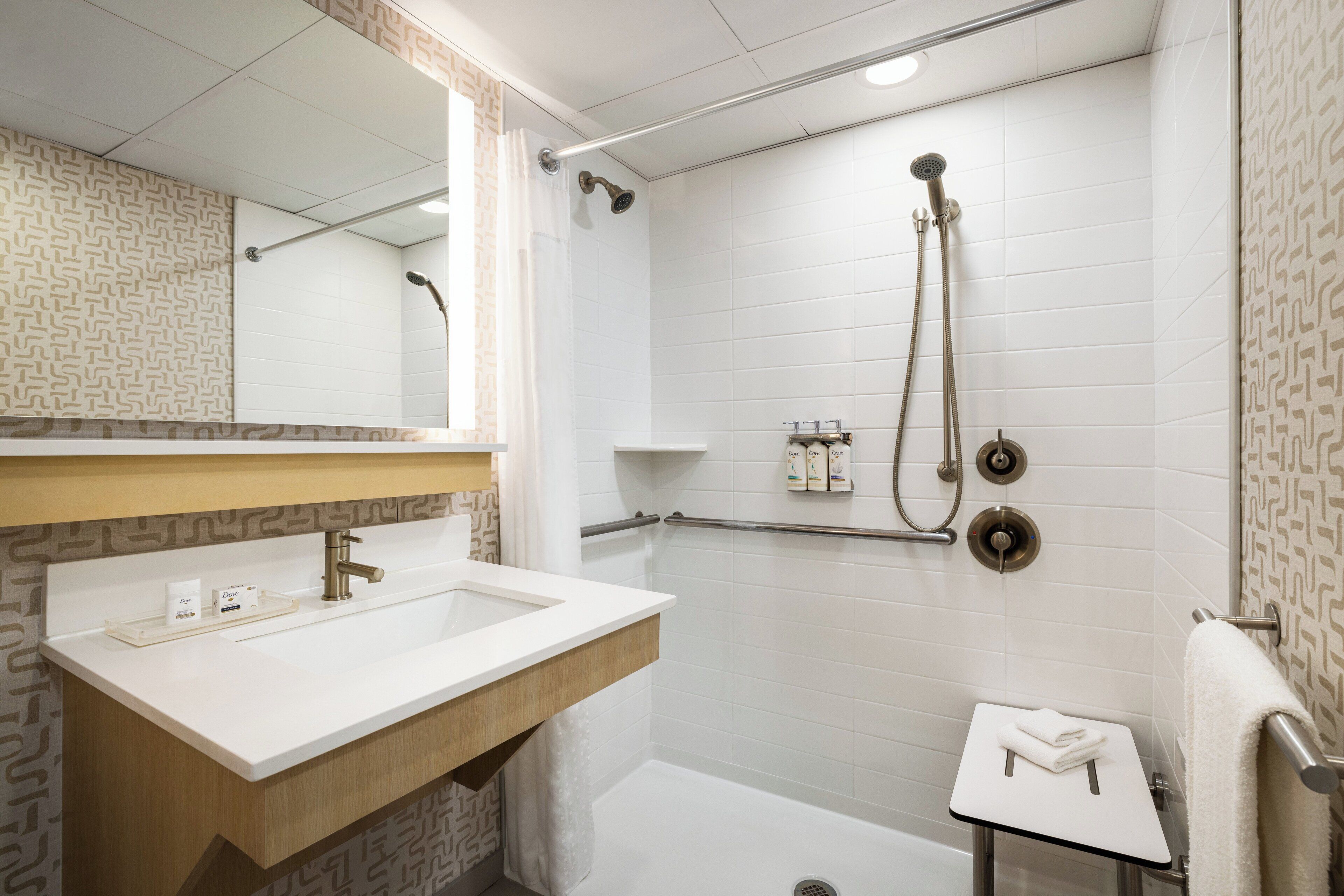 Un bagno moderno con lavandino, specchio e doccia bianchi.