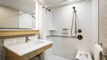 Un bagno moderno con lavandino, specchio e doccia bianchi.