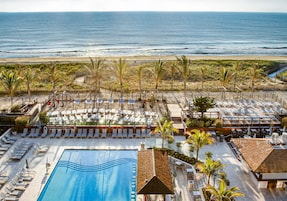 Um resort com piscina, espreguiçadeiras e vista para o oceano.