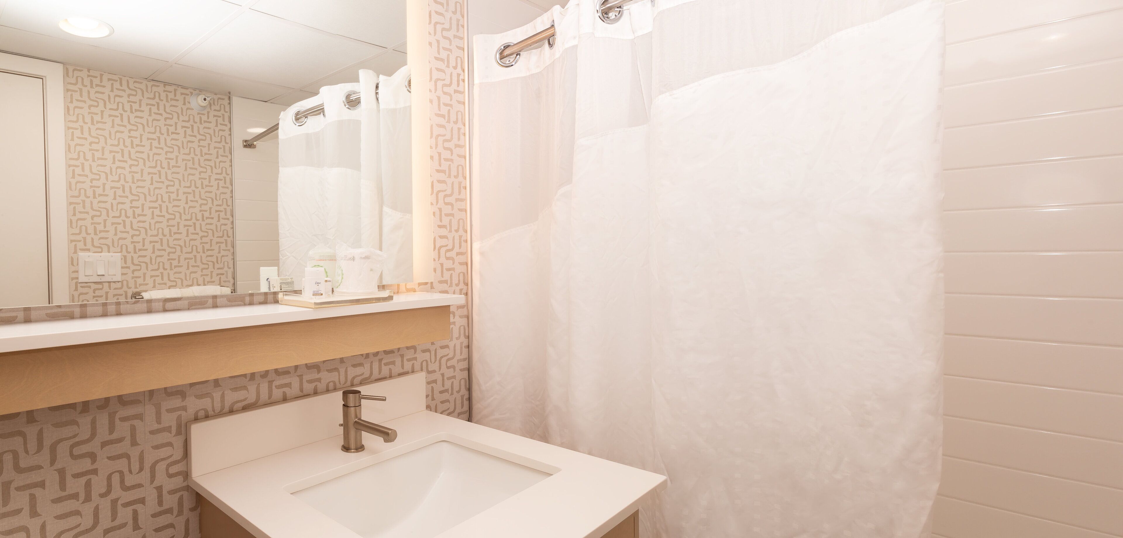 Un baño con lavabo, espejo y cortina de ducha.