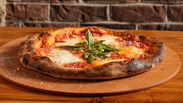 A pizza on a wooden table with a brick wall background.