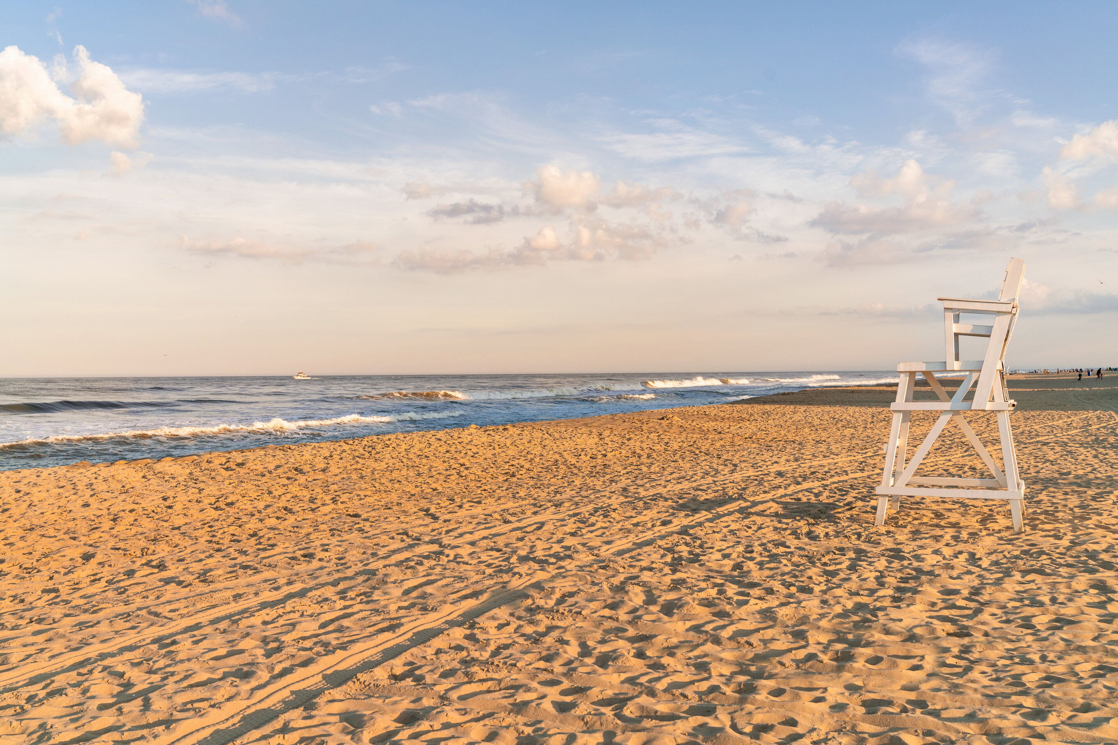 A beach with a lifeguard chair and a boat in the distance.