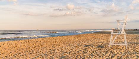 A beach with a lifeguard chair and a boat in the distance.