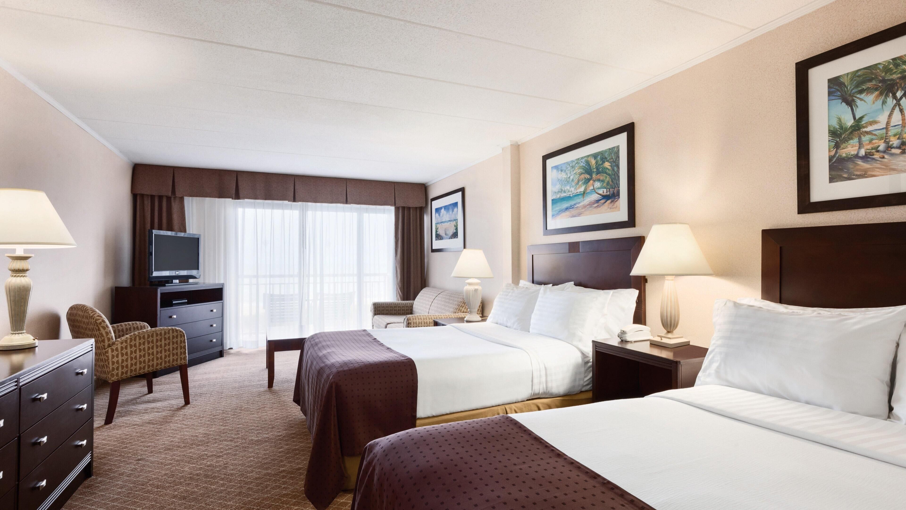 A hotel room with two beds, a TV, a desk, and a chair.
