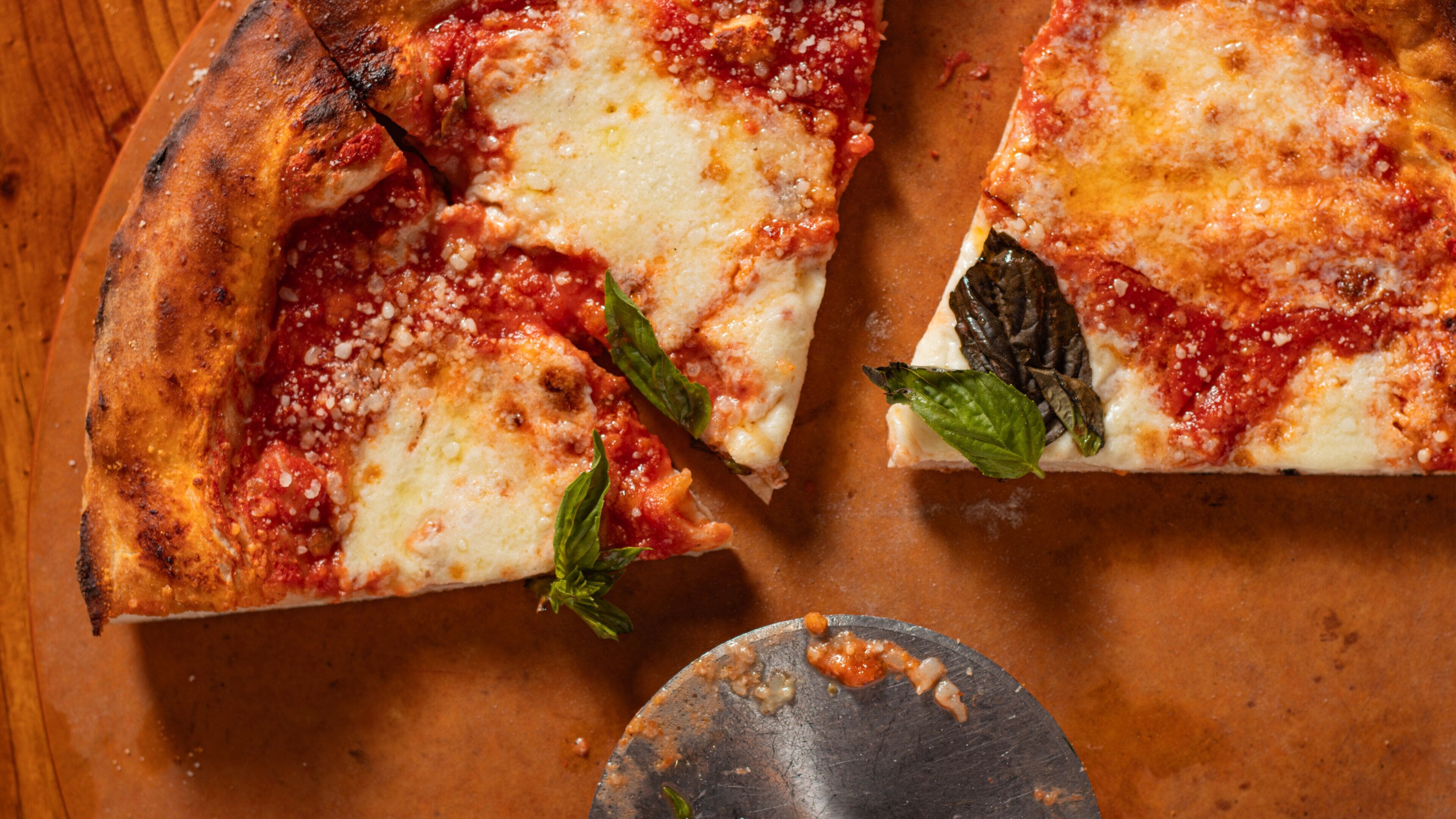 A pizza with cheese and basil leaves on a wooden surface.