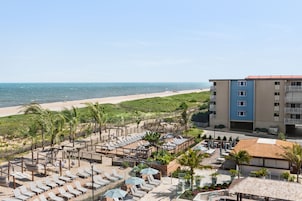 Um resort à beira-mar com espreguiçadeiras, guarda-sóis e vista para o oceano.