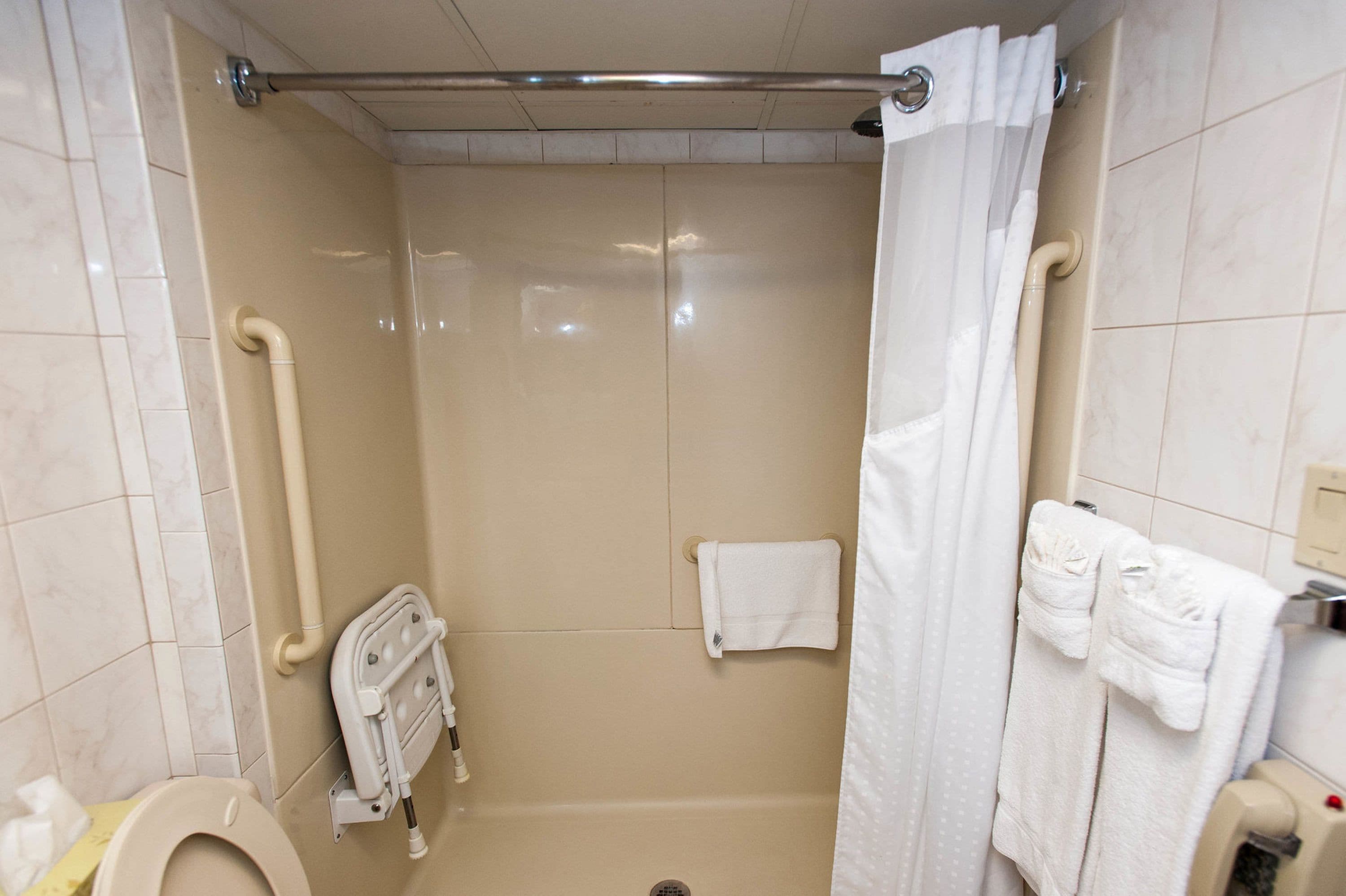 A bathroom with a walk-in shower, a toilet, a towel rack, and a hand dryer.