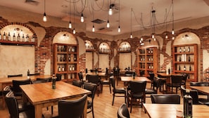 A restaurant interior with brick walls, wooden tables, and shelves of wine bottles.