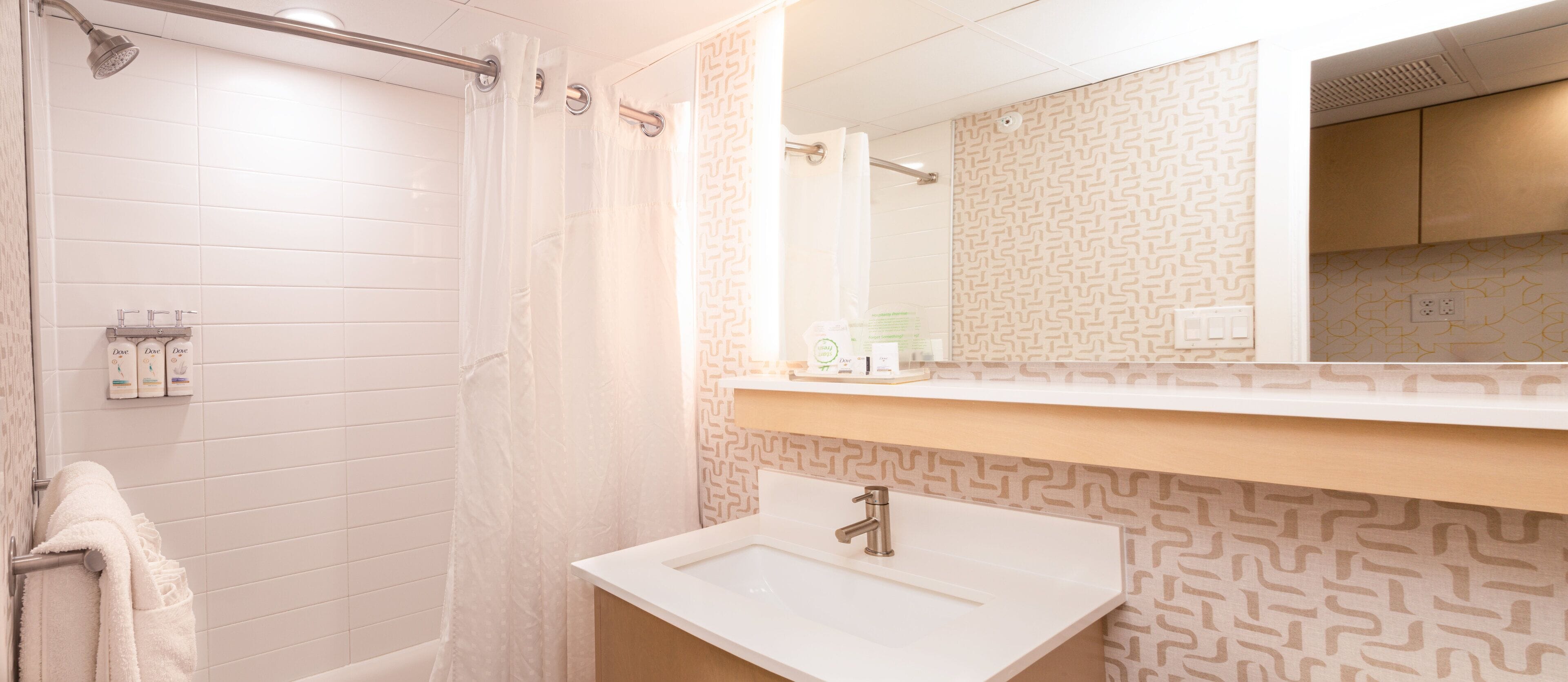 A bathroom with a shower, a sink, and a mirror.
