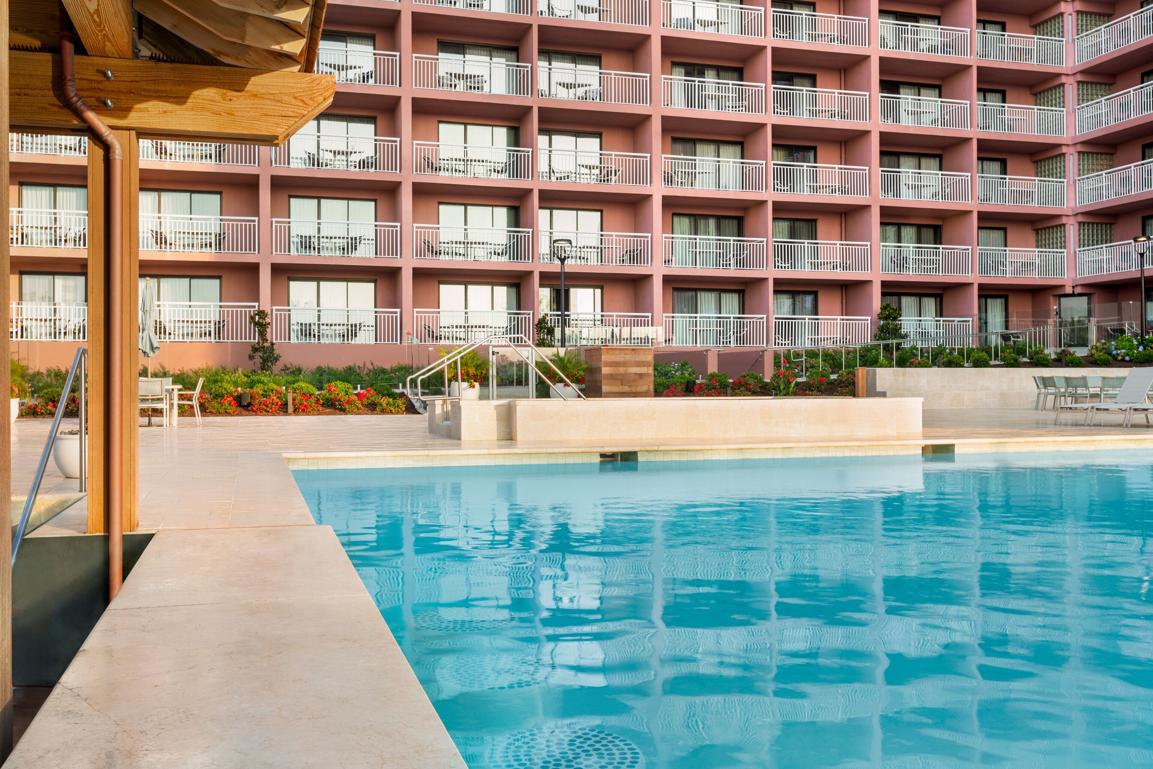 Un hotel con piscina, varios balcones y un jardín bien cuidado.