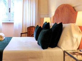 A neatly made bed with dark pillows, a wooden headboard, and a bedside table with a lamp.