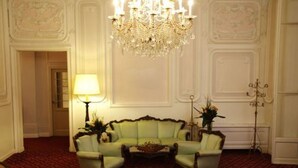 Une pièce avec un canapé vert, un lustre et une lampe.