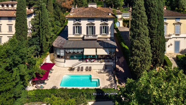 Une villa avec piscine, entourée de grands arbres et d’un jardin bien entretenu.