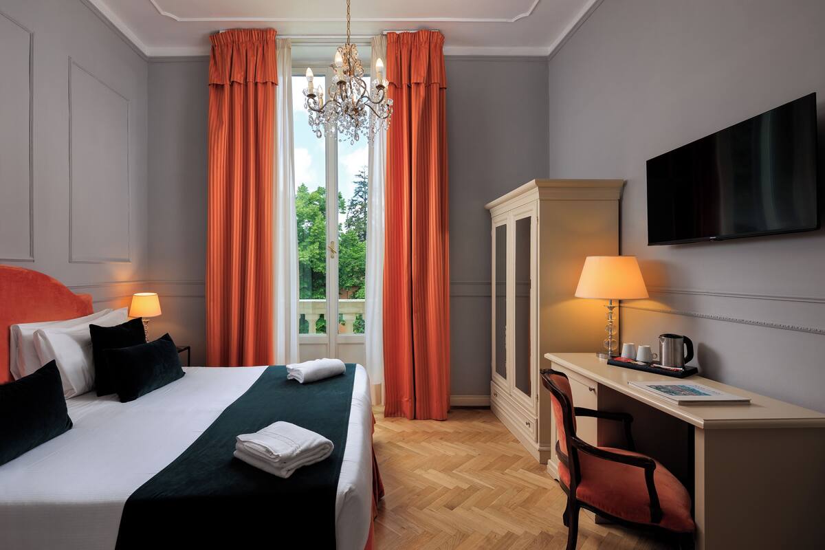 A hotel room with a bed, desk, chair, and TV.