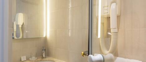 A bathroom with a glass-enclosed shower, a sink with a marble countertop, and a towel rack with a white towel.
