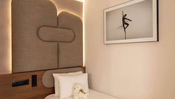 Un dormitorio con cabecera, cama con almohadas, un osito de peluche y un cuadro en la pared.