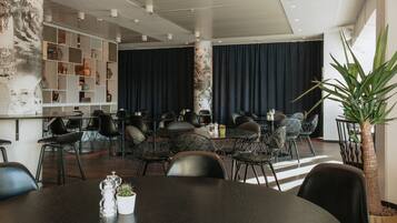 Un comedor moderno con sillas negras, una mesa redonda y una pared decorativa con estantes.