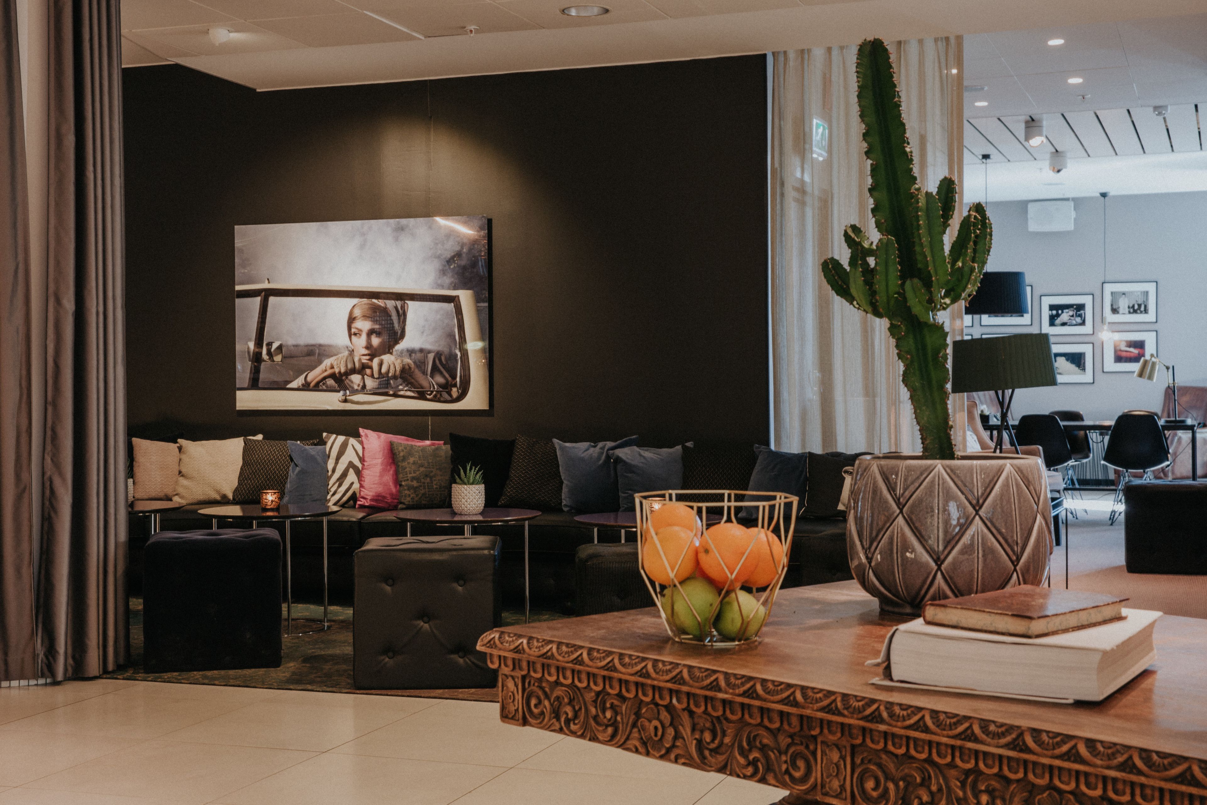 Una sala de estar moderna con un sofá, una mesa baja con fruta, un cactus y un cuadro en la pared.
