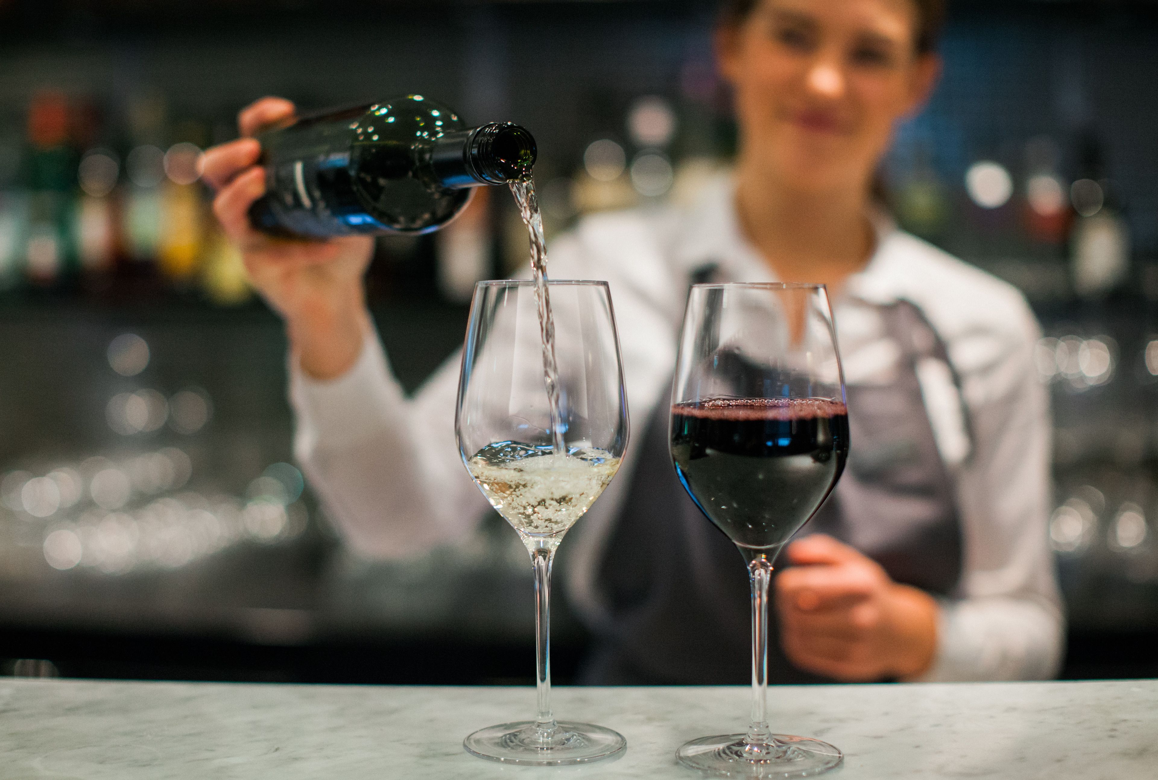 Un barman verse une boisson dans un verre à vin.