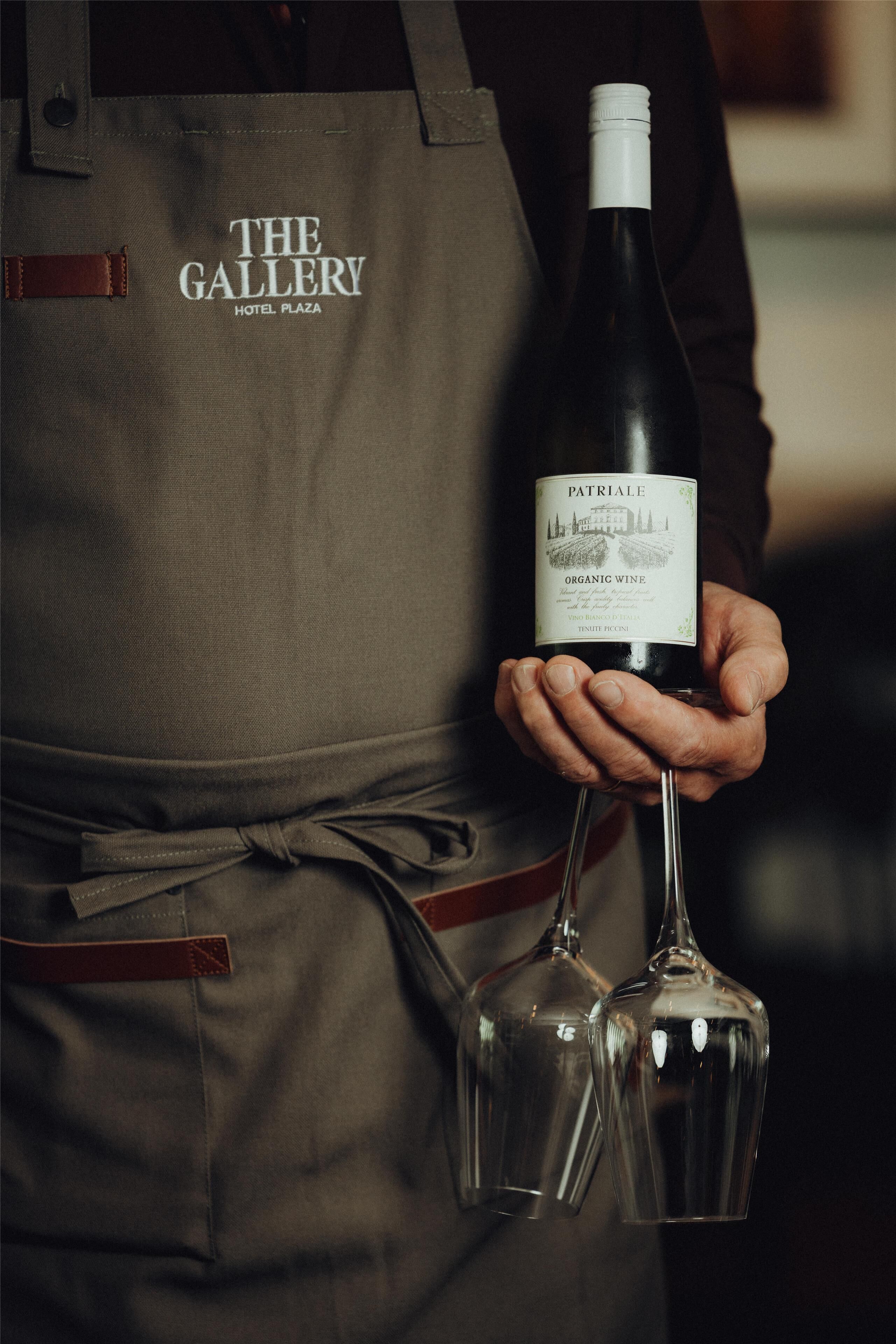 Une personne tenant une bouteille de vin biologique et deux verres à vin.