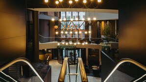 Un intérieur moderne avec un bar central, des espaces pour s’asseoir et un escalier mécanique.