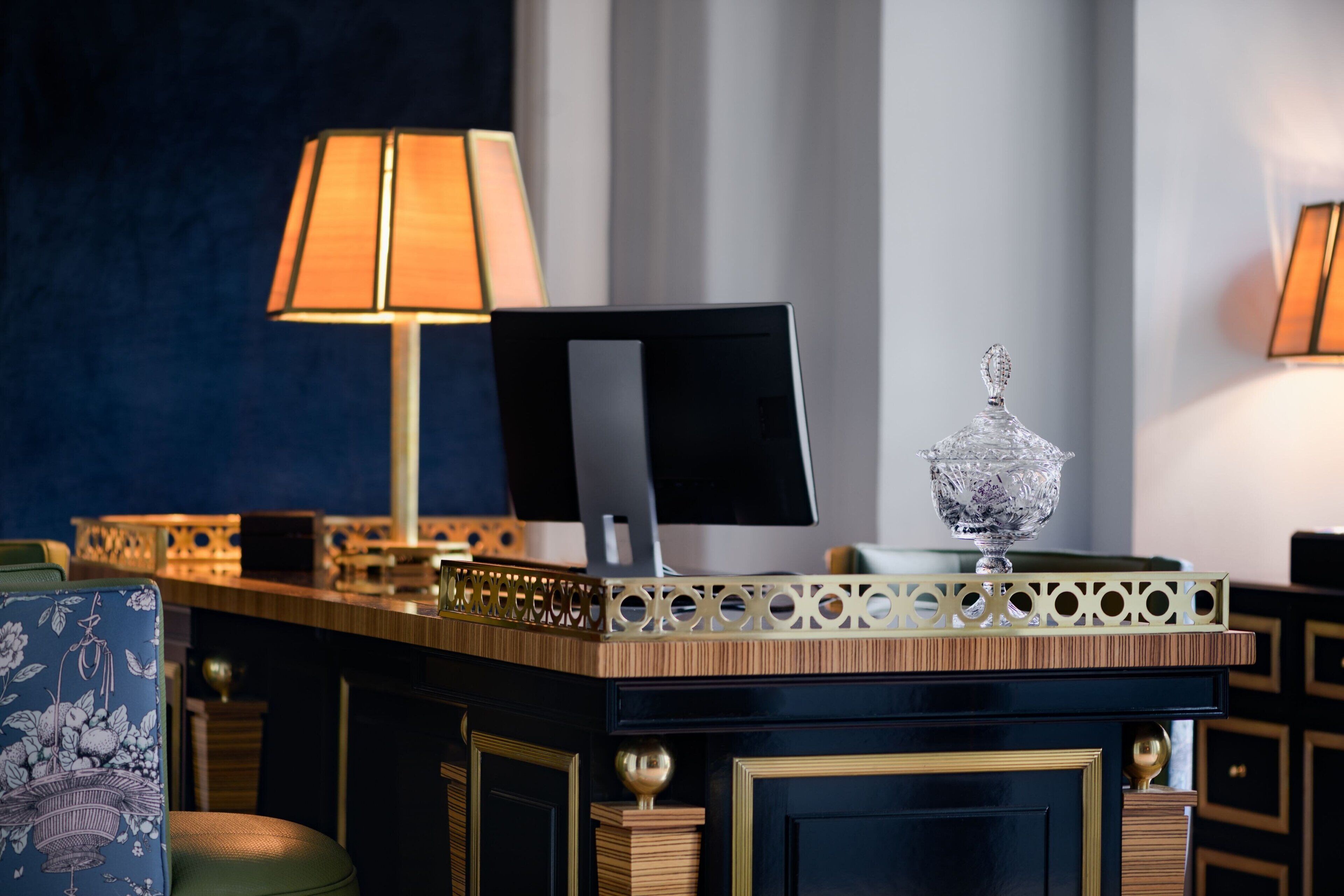 Un mostrador de recepción de hotel con una computadora, adornos y una lámpara.