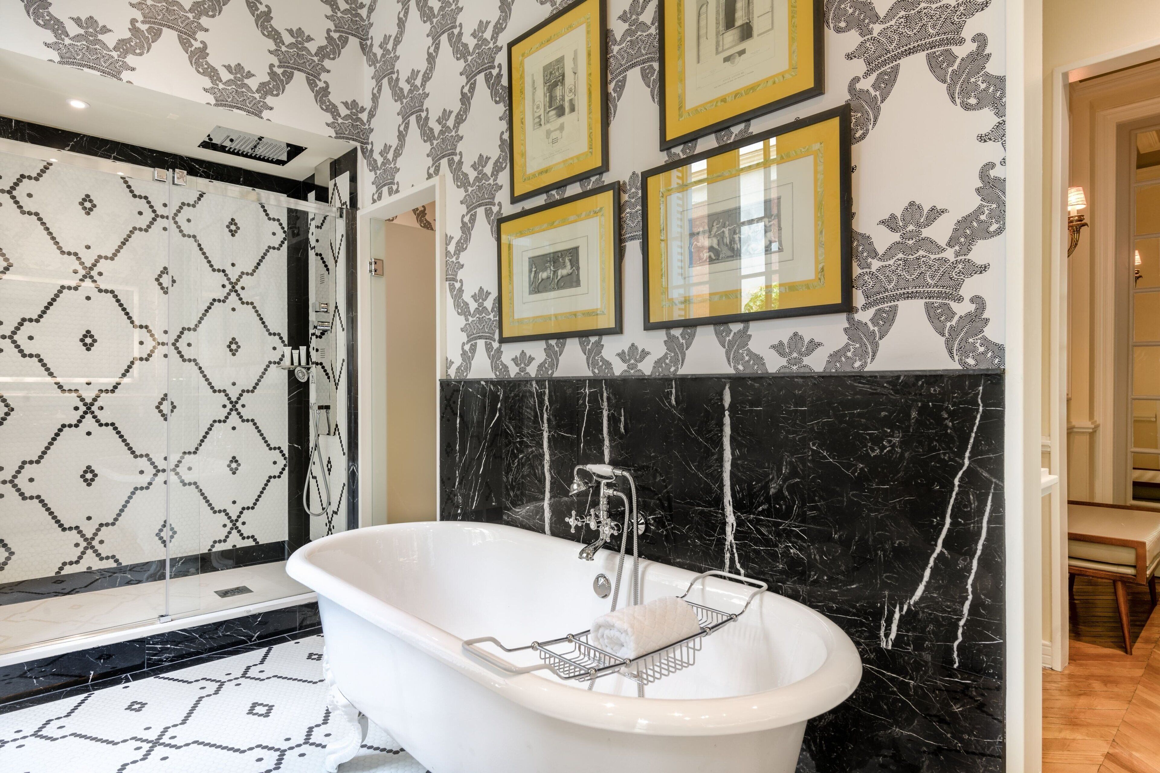 A bathroom with a freestanding bathtub, a shower with patterned tiles, and framed pictures on the wall.