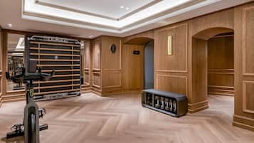 A gym with exercise equipment, wooden paneling, and a herringbone floor pattern.