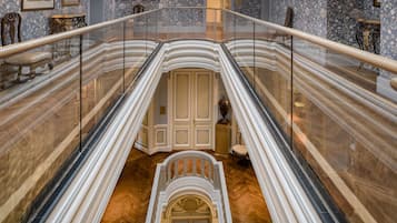 Una imponente escalera con barandilla de cristal que desciende a un nivel inferior.