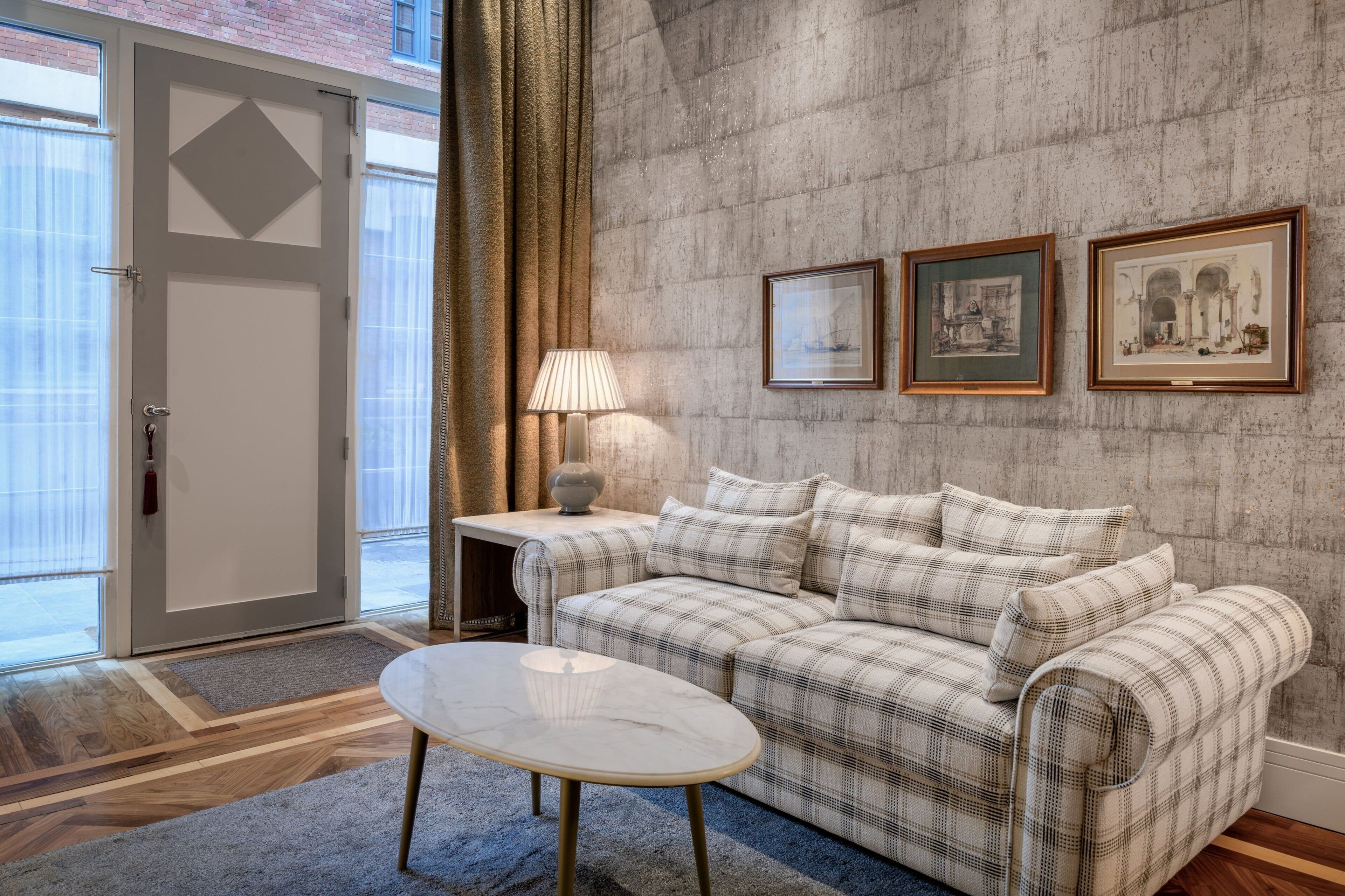 A modern living room with a plaid sofa, a small round table, and two framed pictures on the wall.