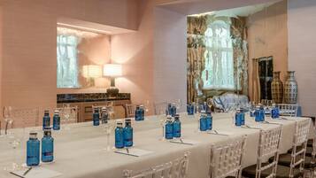 A conference room with a long table set for a meeting, clear chairs, and blue water bottles on the table.